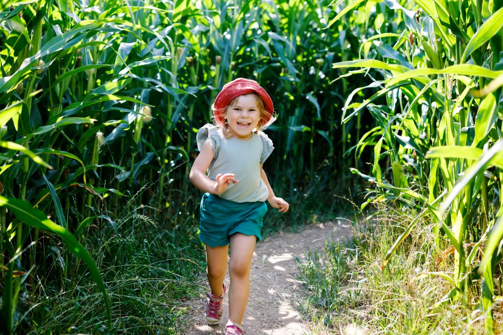 girl running through corn maze smiling